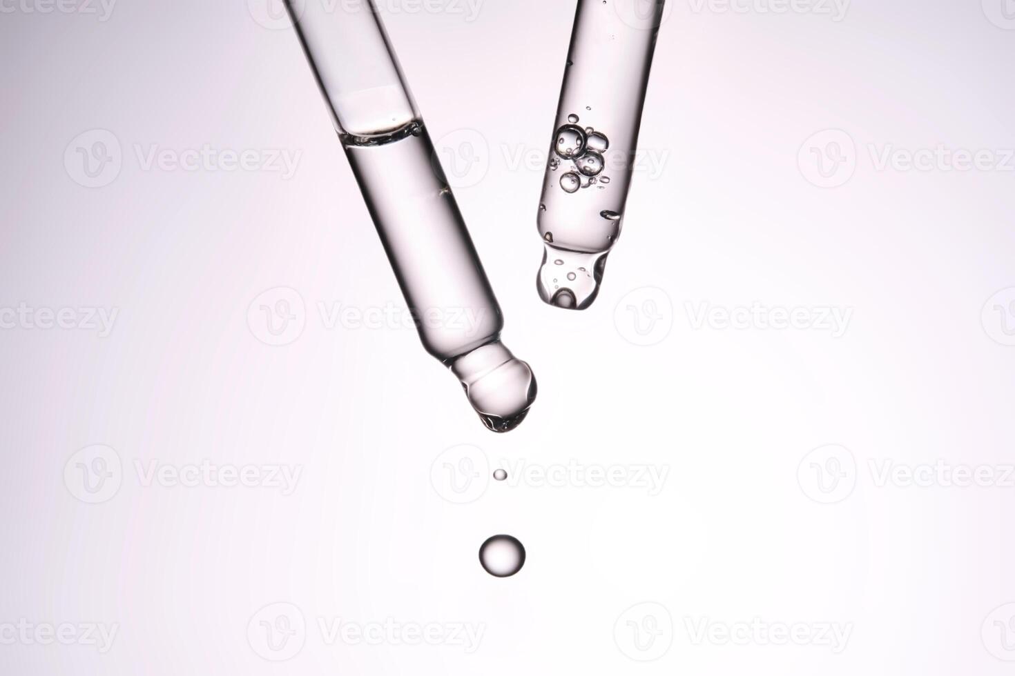 Two pipettes with a cosmetic product. Serum or fluid drips from one of them. photo