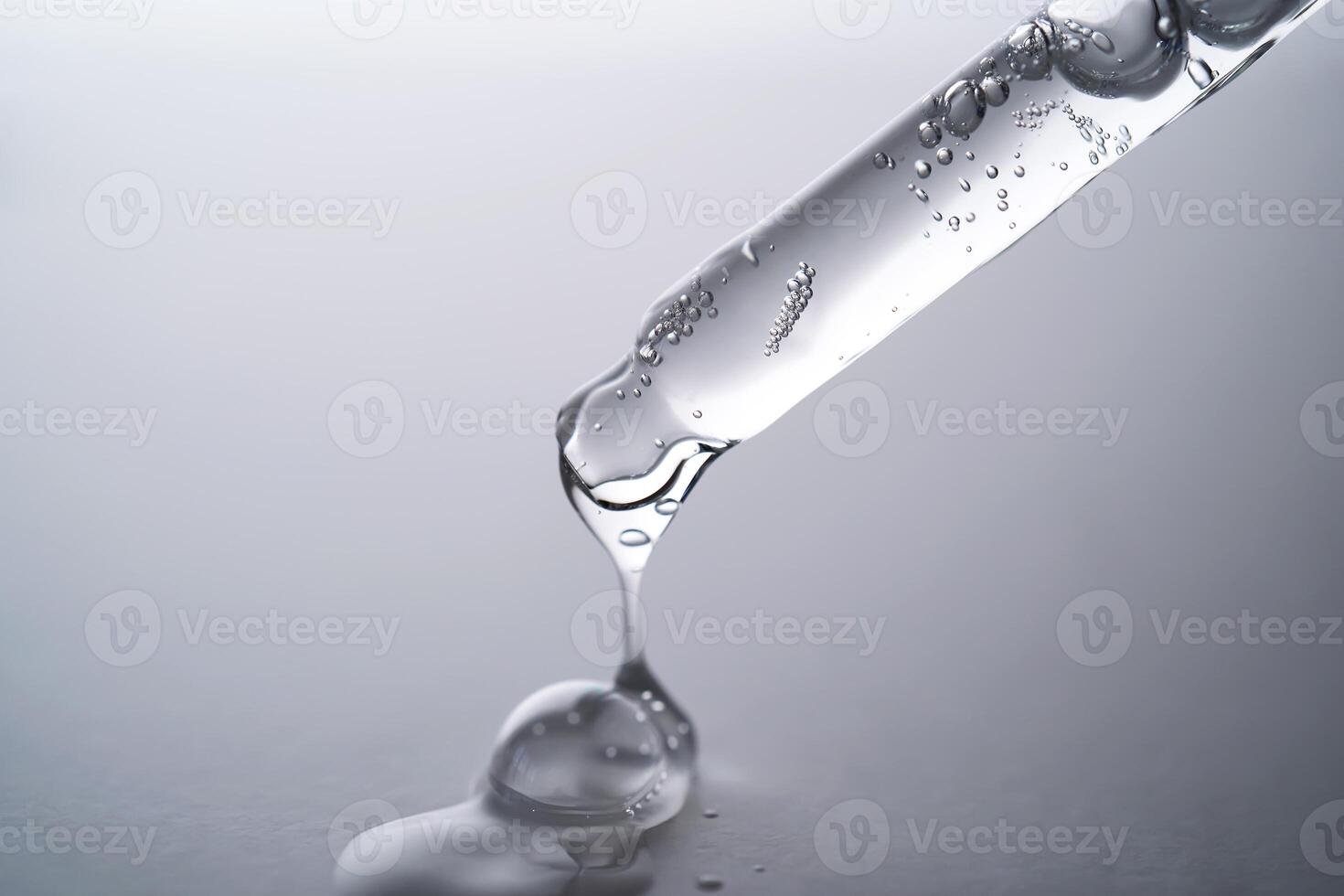 Pipette with facial serum pouring out of it on grey background. photo