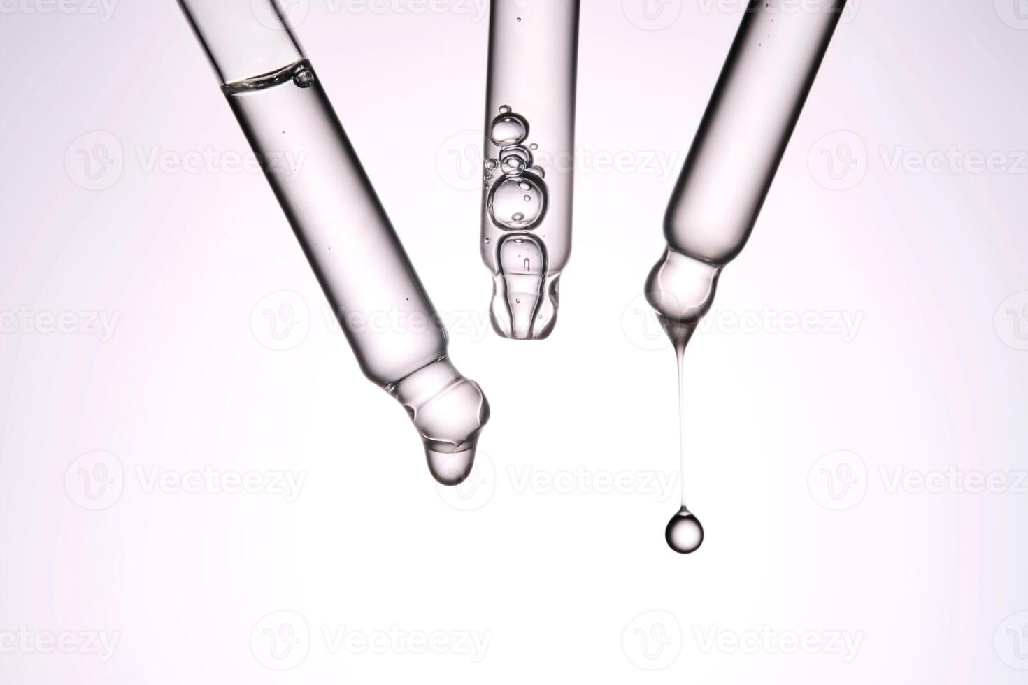 Three pipettes with a cosmetic product. Serum or fluid drips from one of them. photo