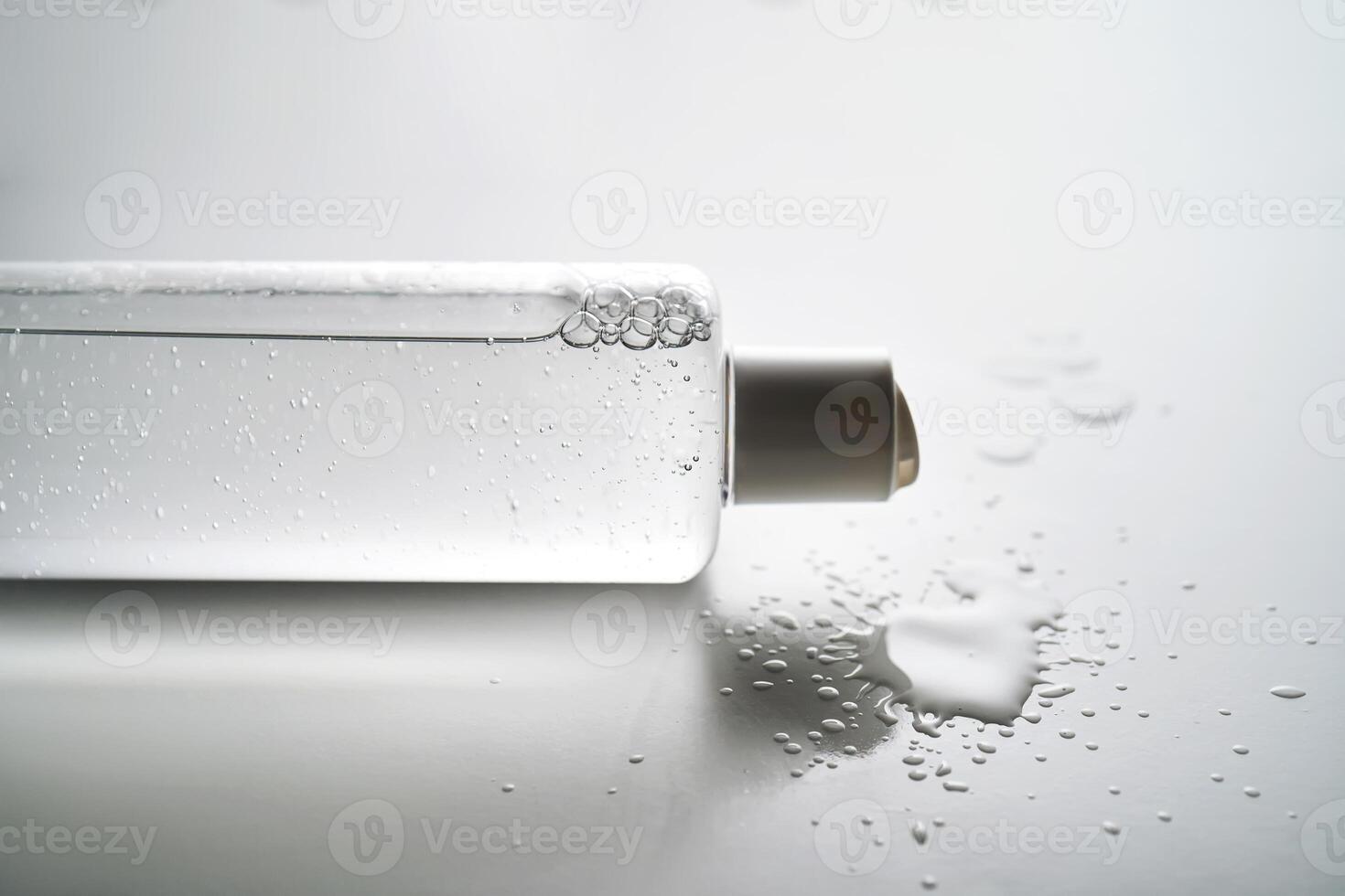 Bottle of facial toner or cleanser on white background with drops of product. photo