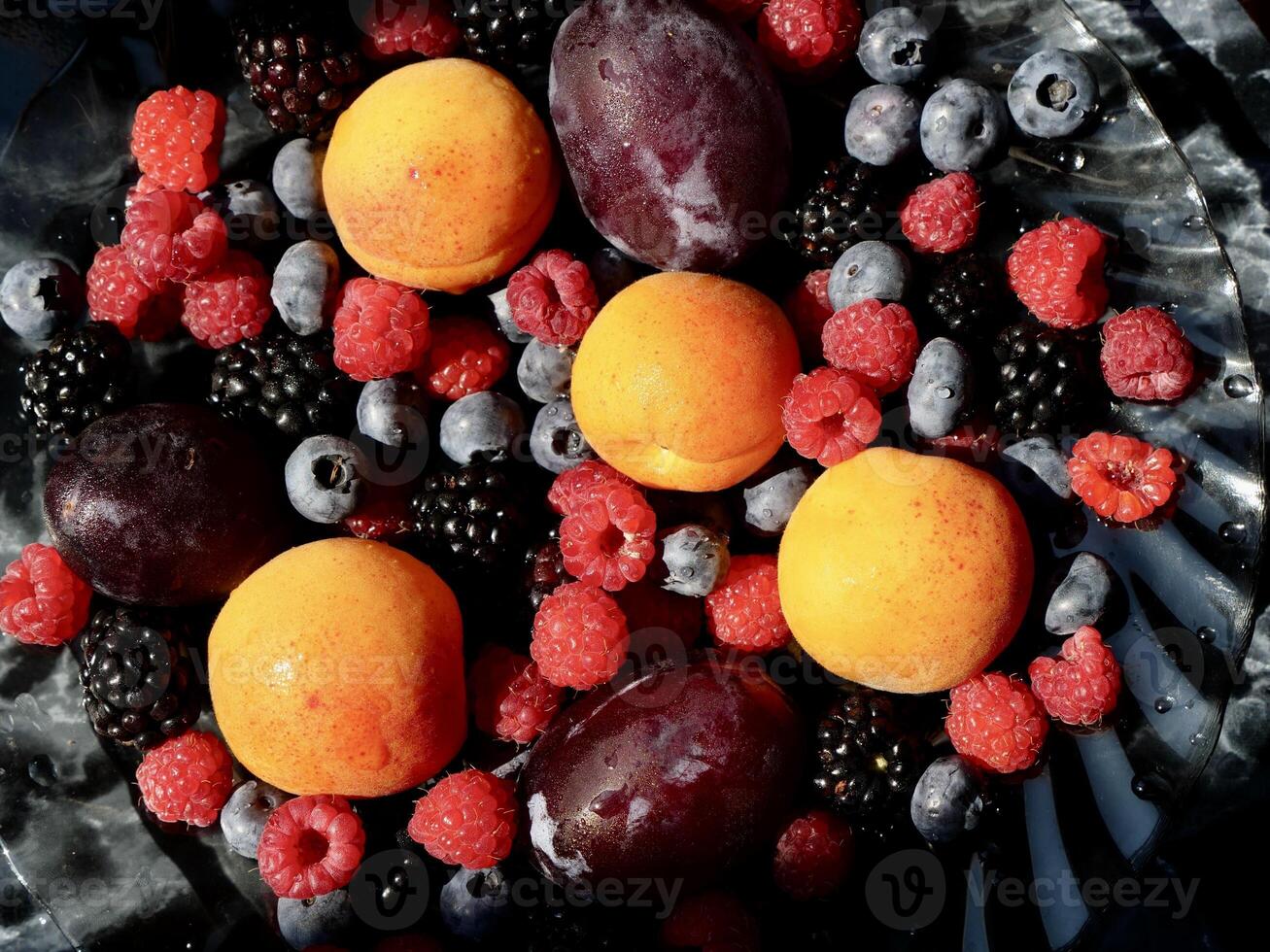 Colored background of seasonal summer fruits apricot, plum, raspberry, blueberry, blackberry in garden, close up photo