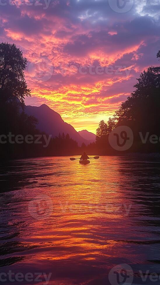 Solitary Kayaker at Sunset with Mountain Silhouette and Rippling Water photo