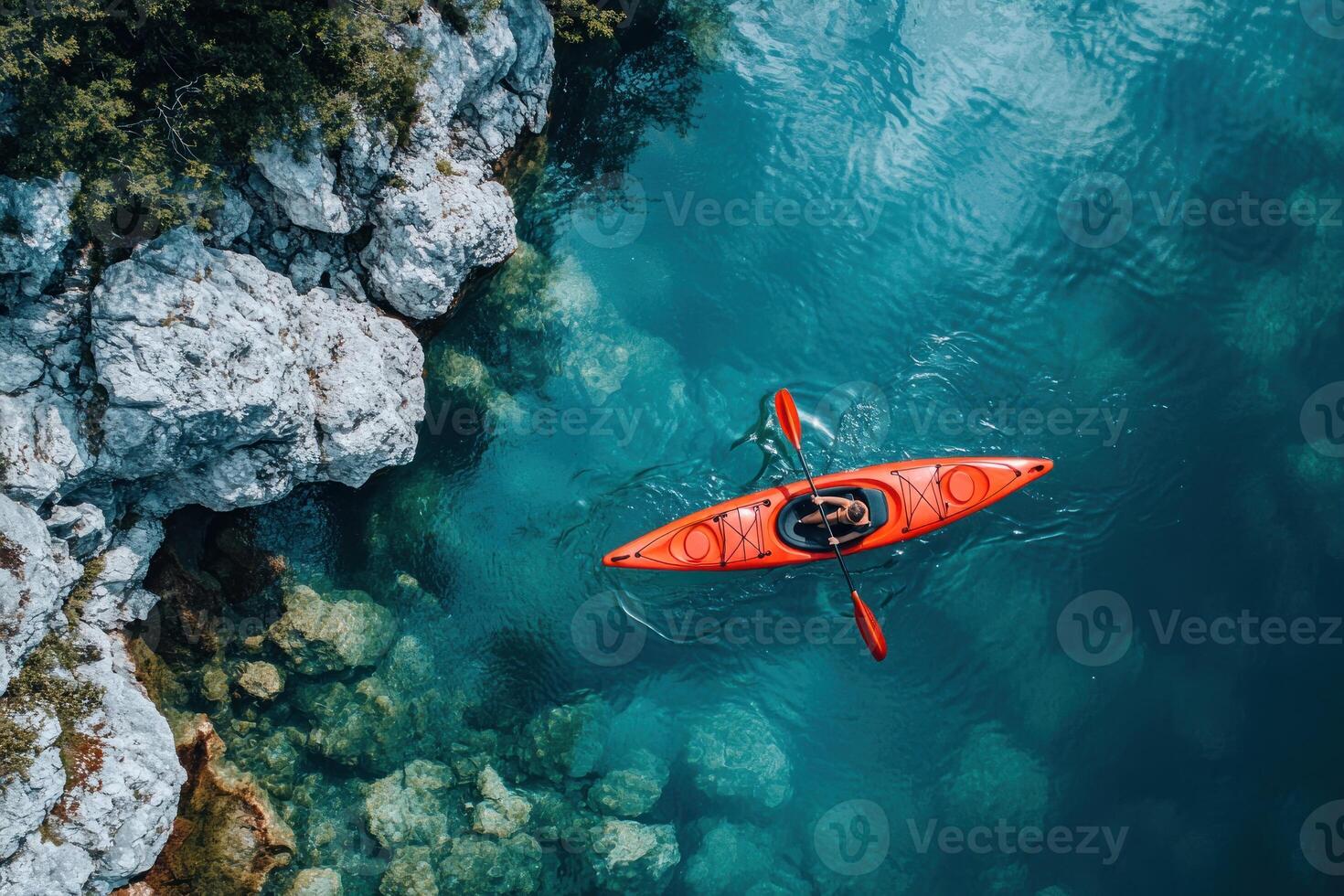 Aerial View of a Single Kayaker Paddling in a Calm Turquoise Lake Surrounded by Rocks photo