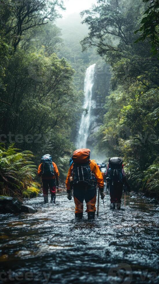 Hikers Walking Through a River and Waterfall in a Lush Forest photo