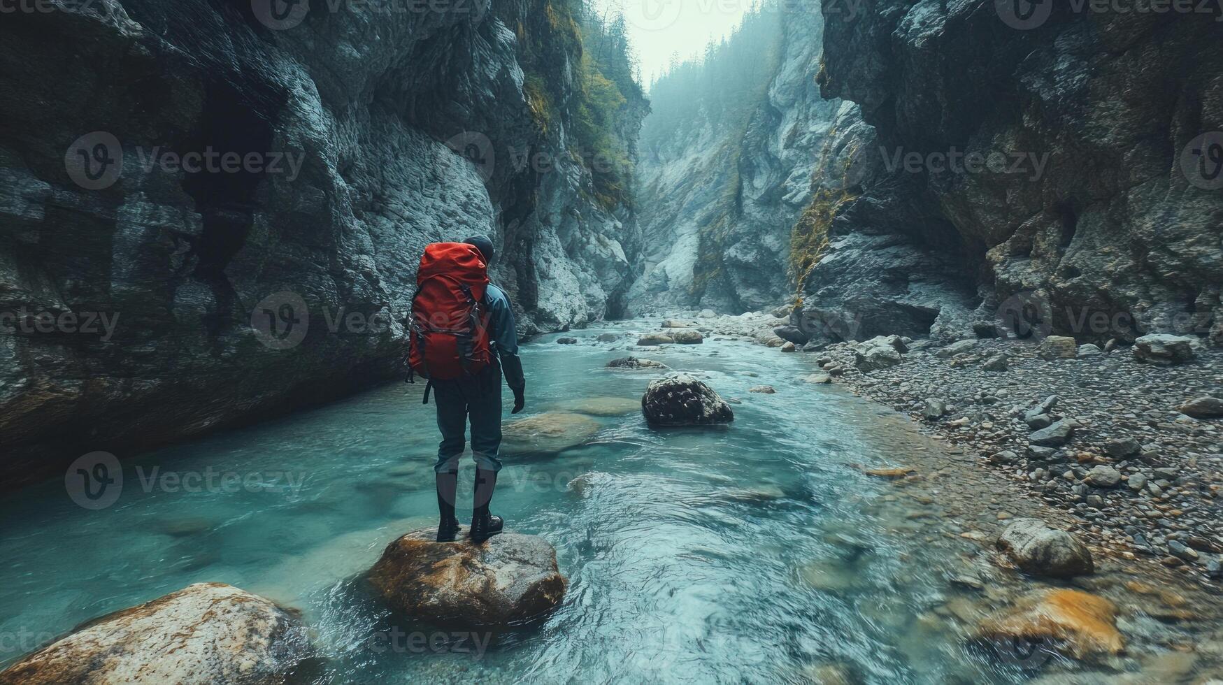 Hiker with Red Backpack Standing on a Rock in a Mountain Gorge photo
