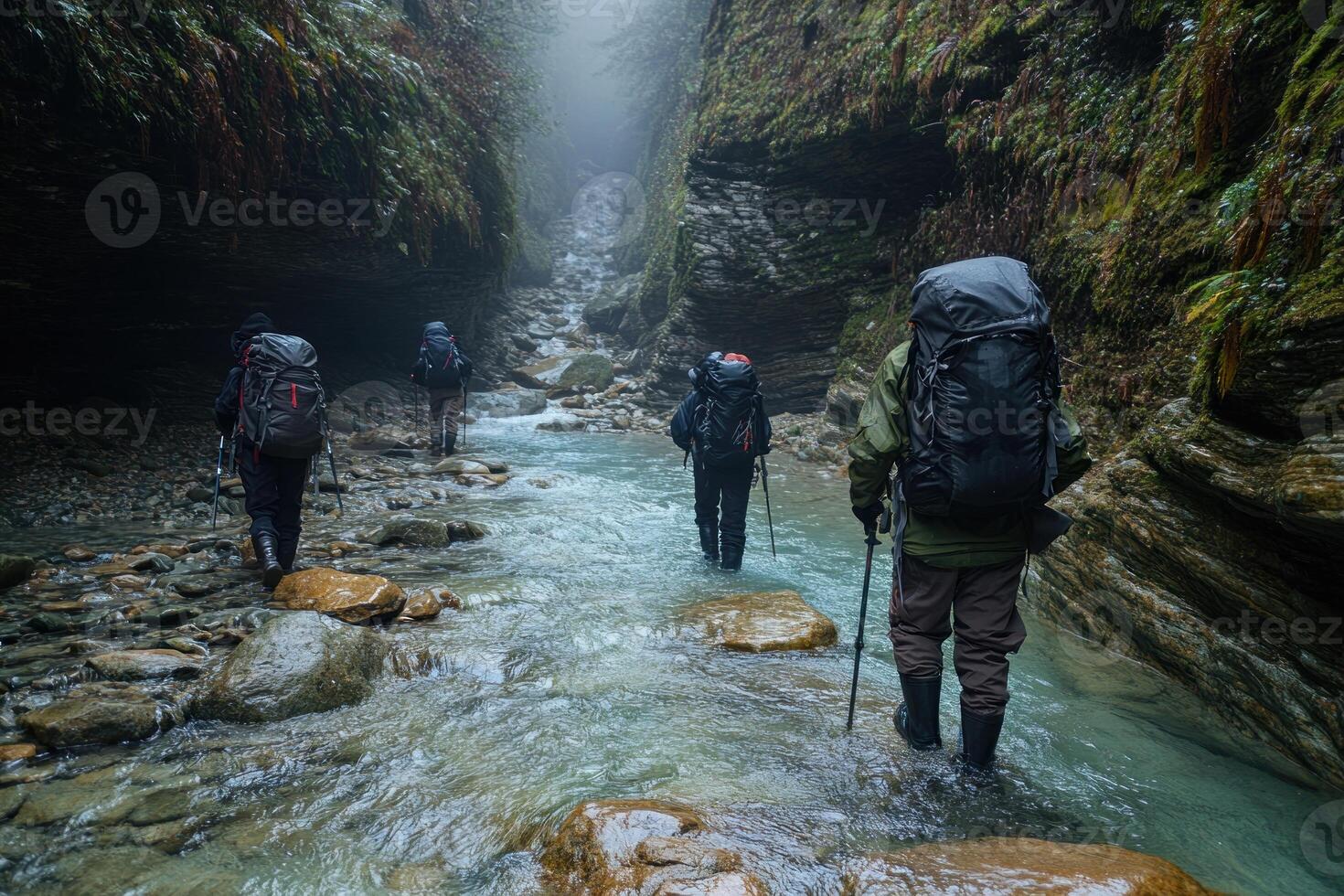 Hikers traverse a misty mountain stream in a narrow gorge. photo