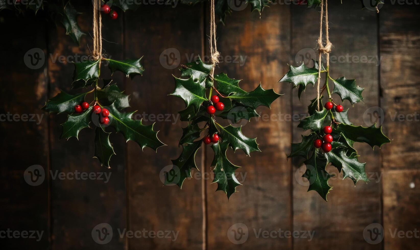 Three branches of holly are hanging from a wooden beam photo