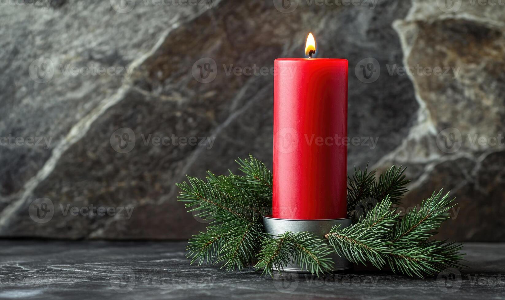 A red candle is lit on a table with pine needles photo