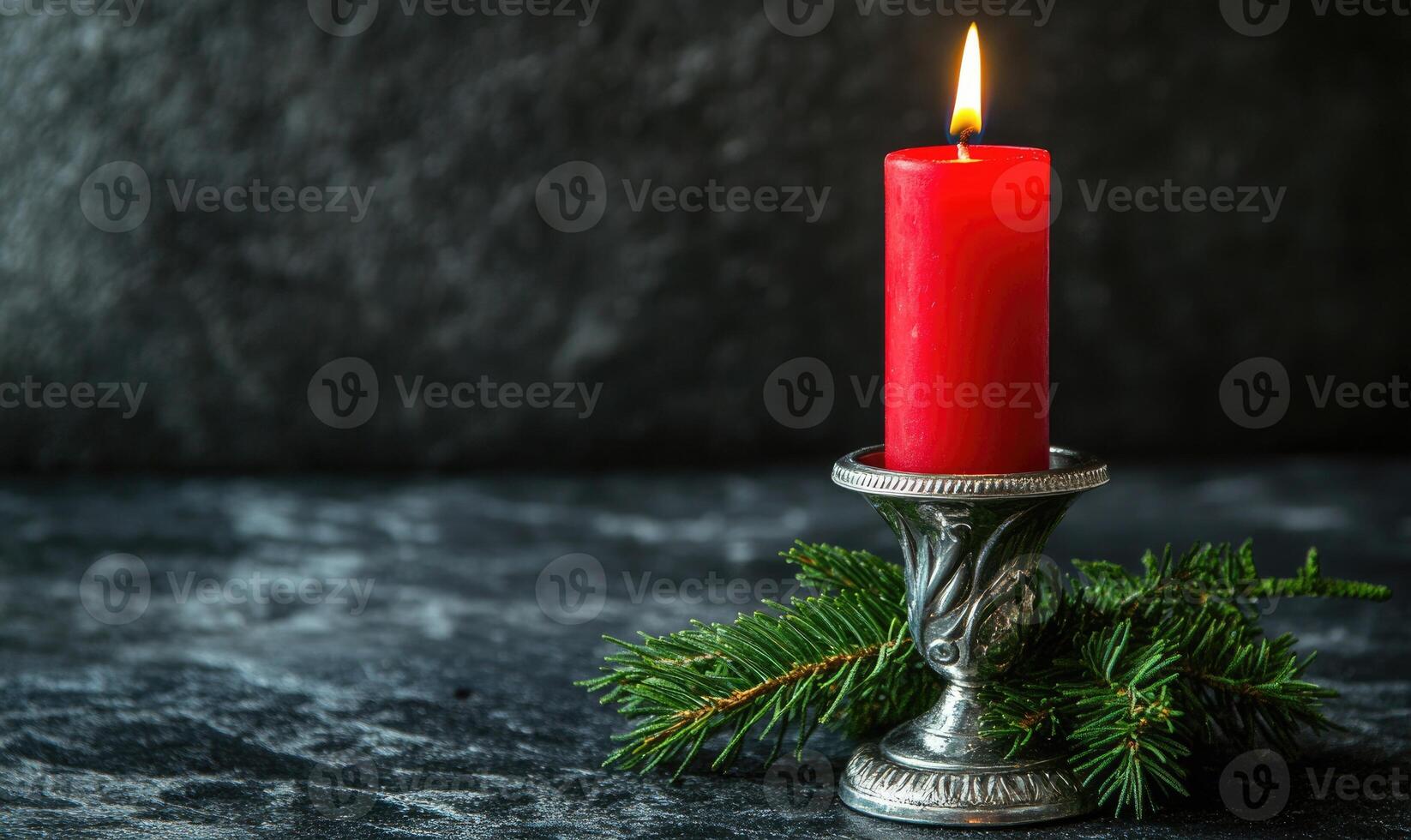 A candle is lit on a table with a pine branch photo