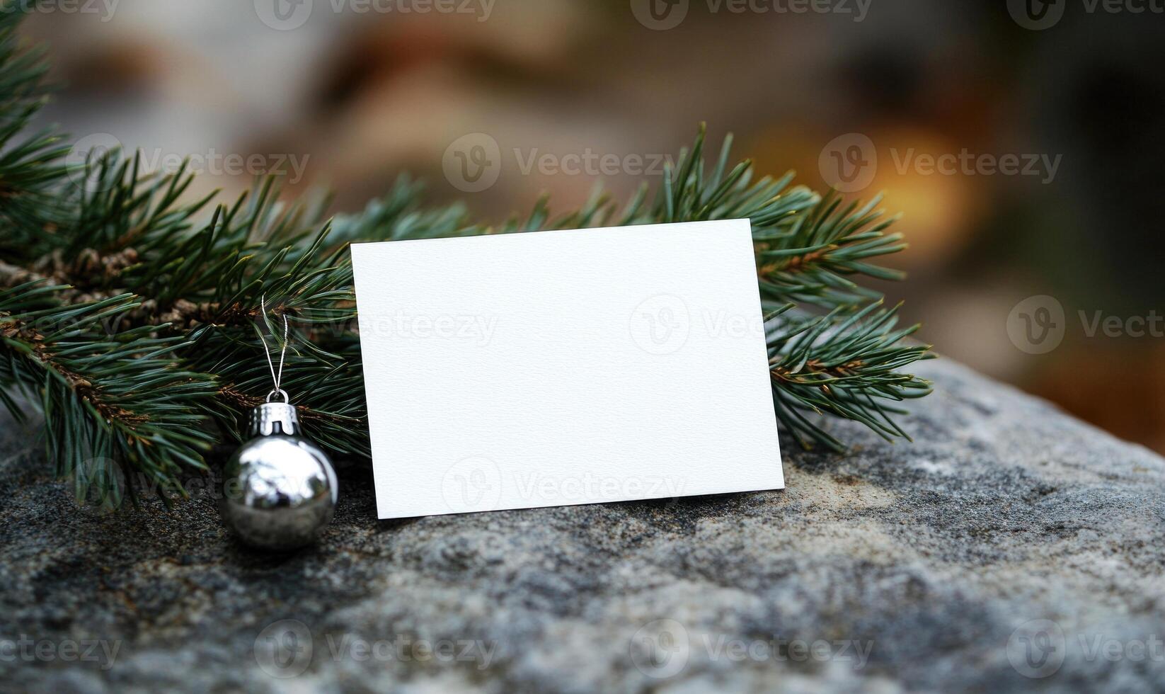 A white card is sitting on a rock next to a Christmas ornament photo