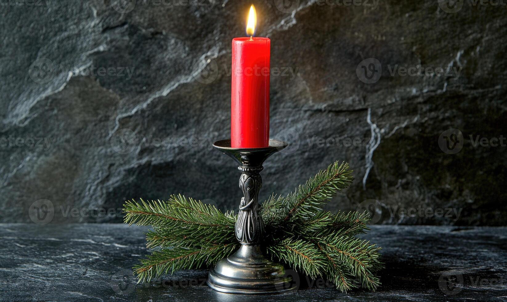 A candle is lit on a silver candle holder with a pine branch photo