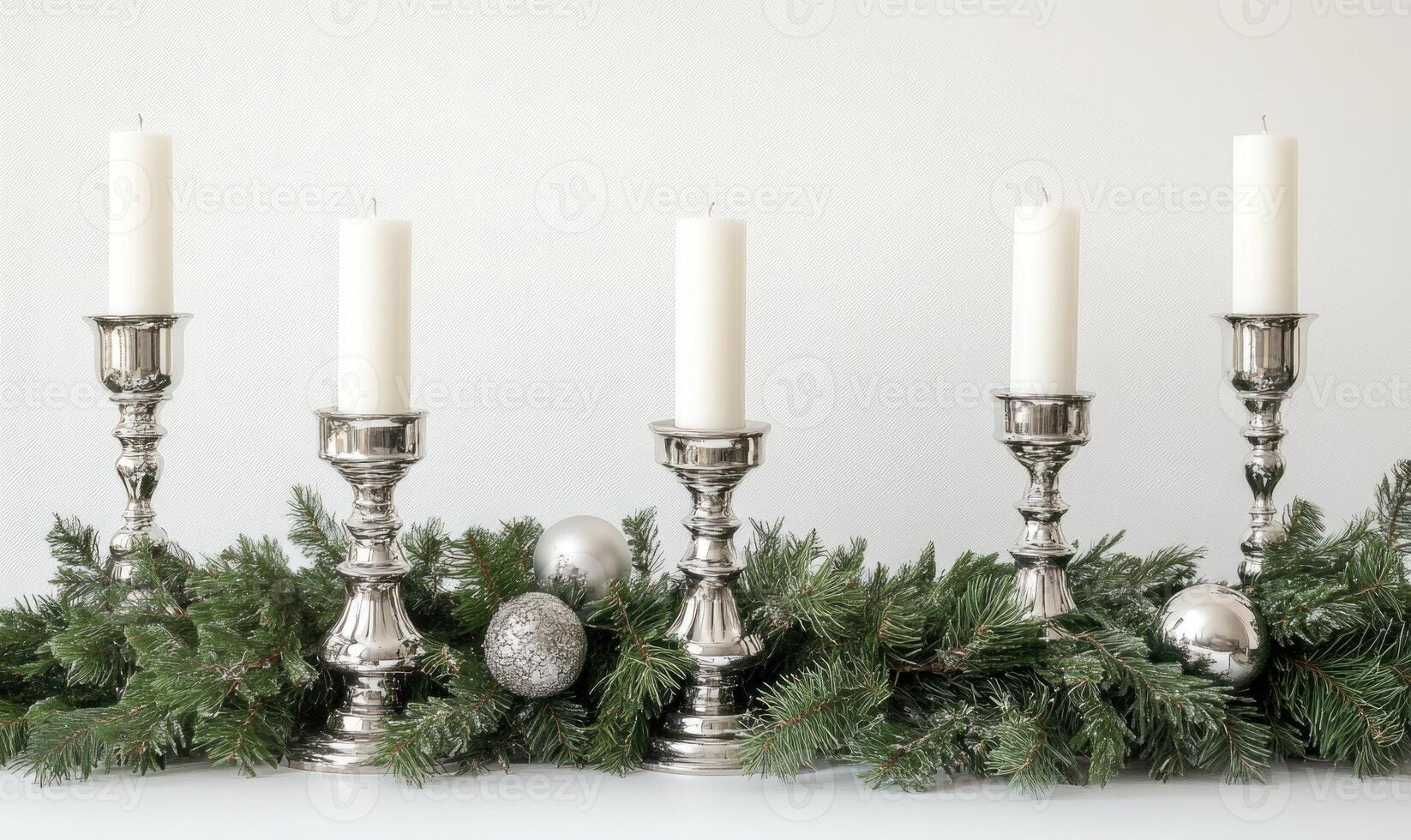 A row of five candles are lit on a table with a Christmas tree decoration photo