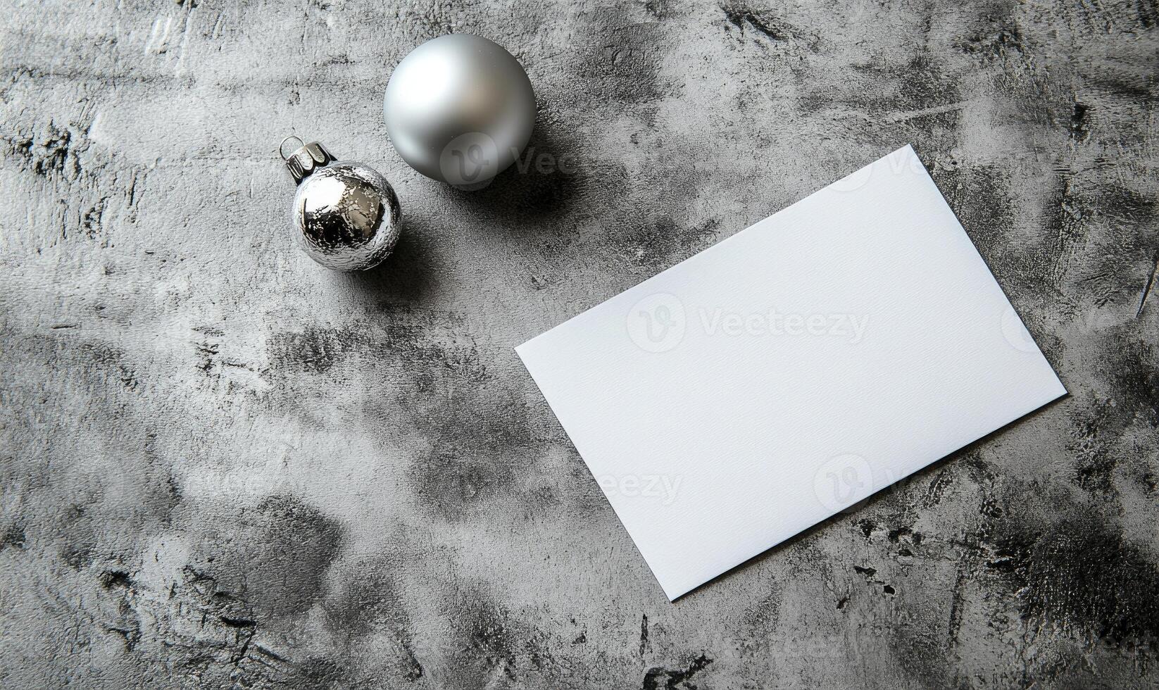 A silver ball and a white card with a blank space sit on a grey surface photo