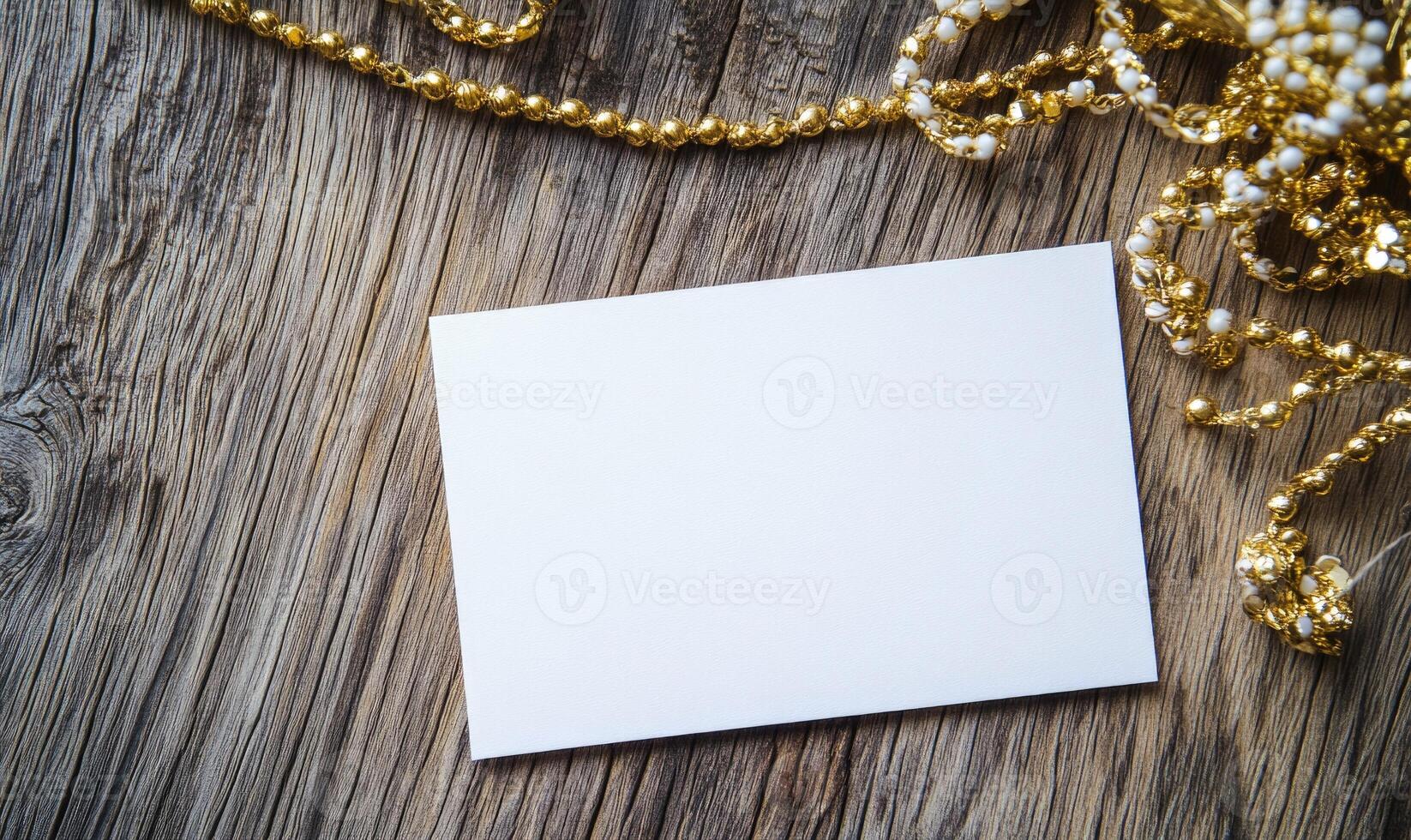 A white card is on a wooden surface with gold beads photo