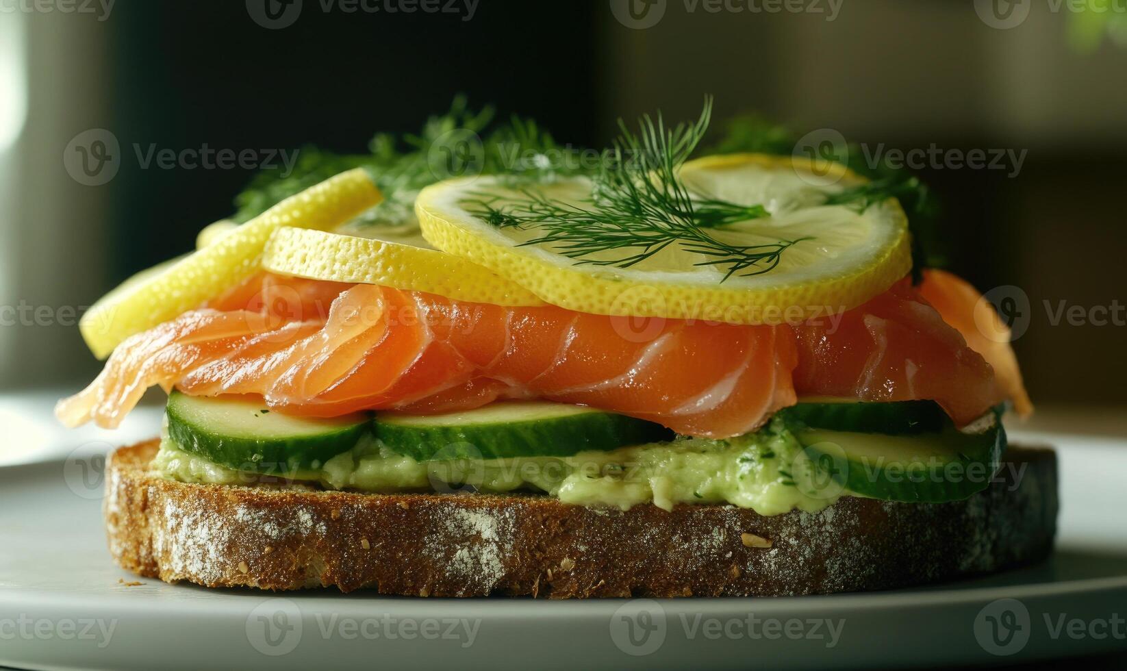 A sandwich with salmon, cucumber, and lemon slices on a white plate photo