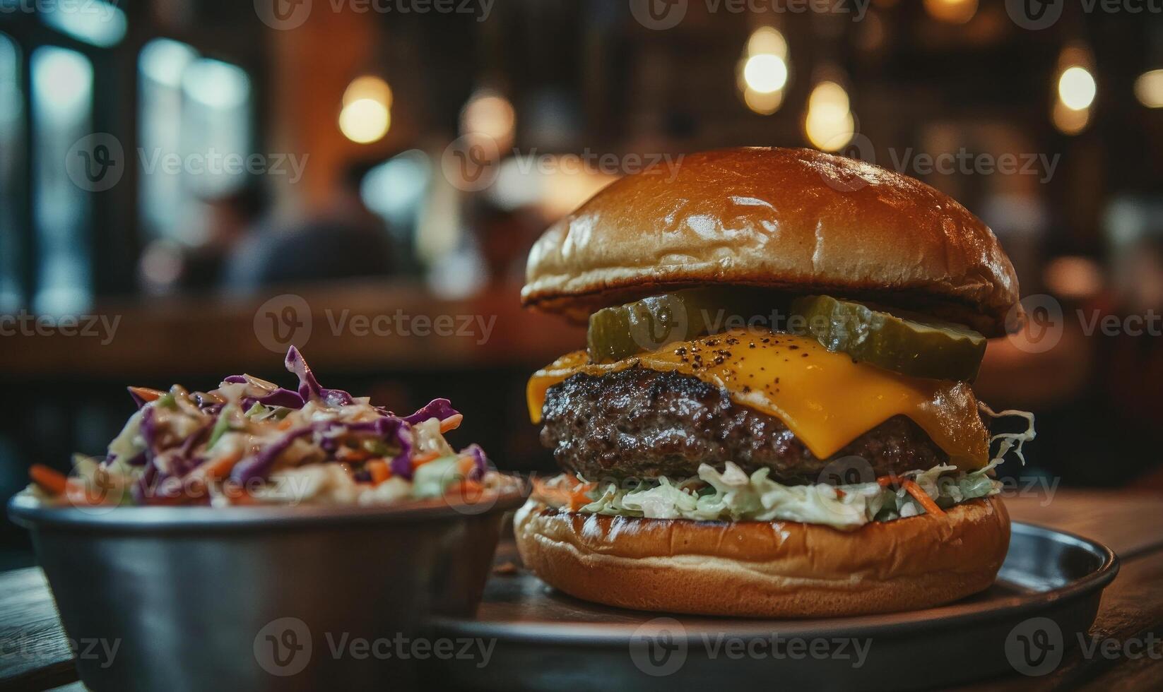 A burger with pickles and cheese sits on a plate next to a bowl of coleslaw photo