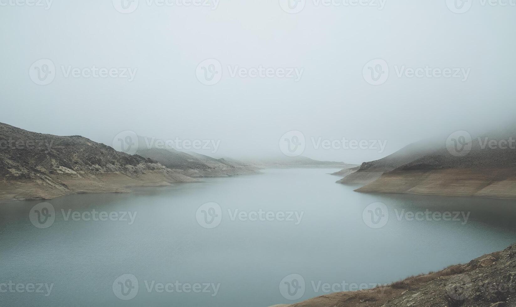 A foggy mountain range with a lake in the foreground photo