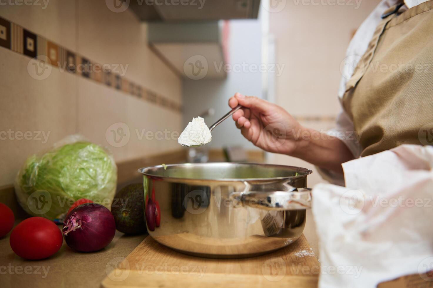 Home cooking. Adding ingredients to a pot on a kitchen counter photo