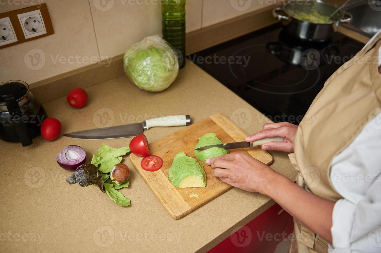 Woman preparing fresh salad with avocado in kitchen photo