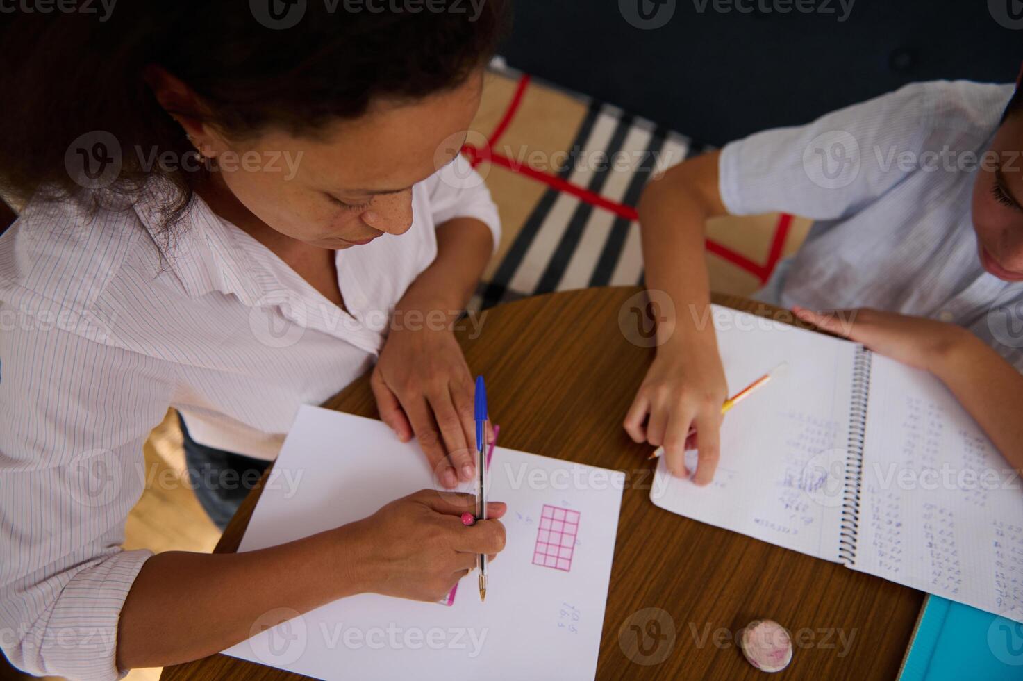 Mother helping child learn math at home on a wooden table photo
