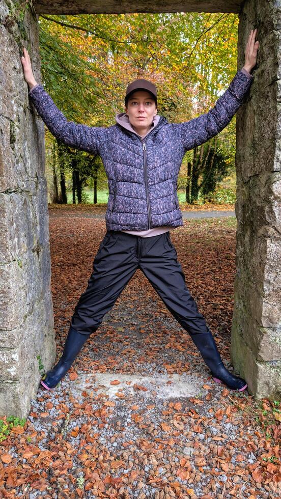 Portrait of pretty hiker girl at medieval stone entrance at Coole park nature reserve at county Galway, Ireland, people background photo