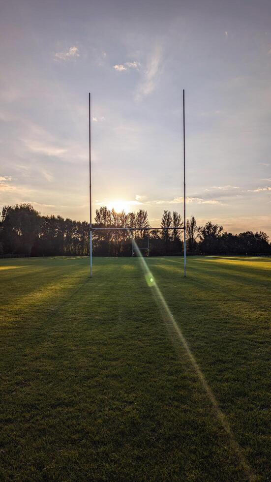 Rugby goalposts on a grassy field at sunset photo