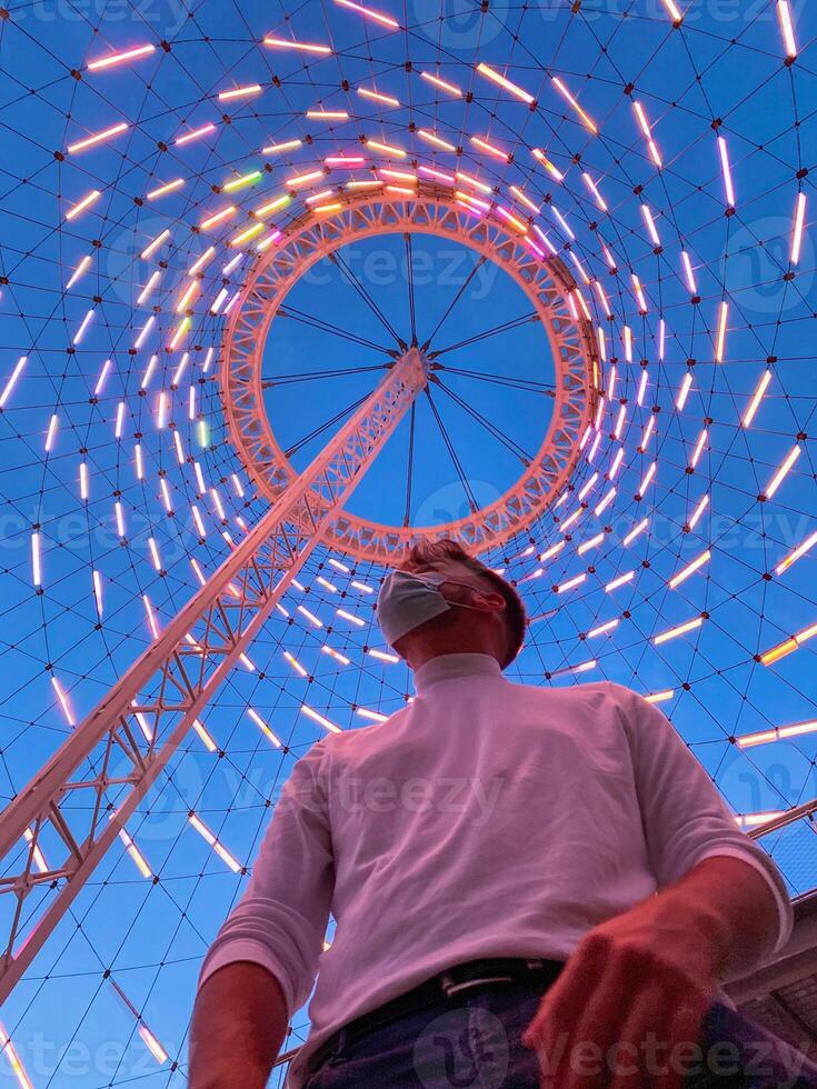 Young masked man standing in light structure photo