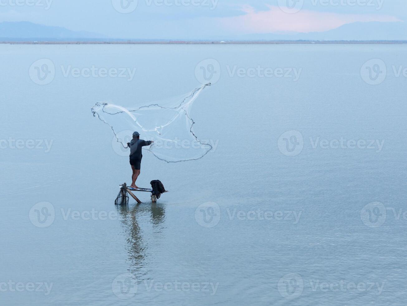 Fisherman catching fish with net on the lake in the morning, Gorontalo, Indonesia photo