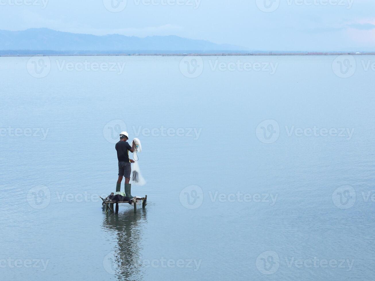 Fisherman catching fish with net on the lake in the morning, Gorontalo, Indonesia photo