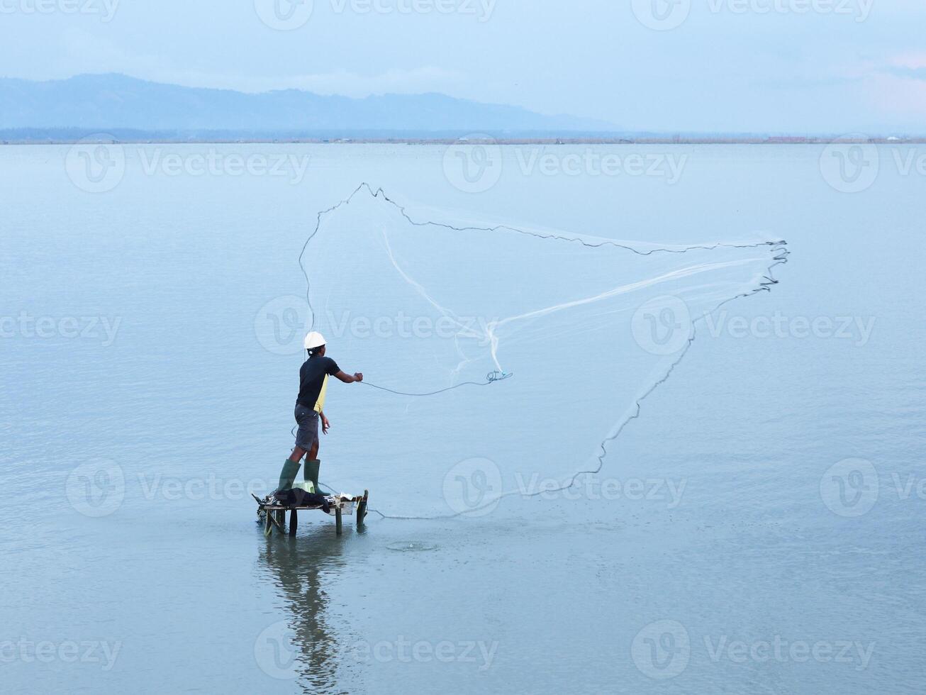 Fisherman catching fish with net on the lake in the morning, Gorontalo, Indonesia photo