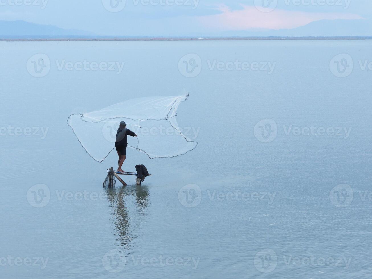 Fisherman catching fish with net on the lake in the morning, Gorontalo, Indonesia photo
