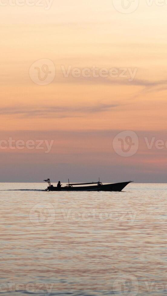 Silhouette of a fishing boat in the sea at sunset photo