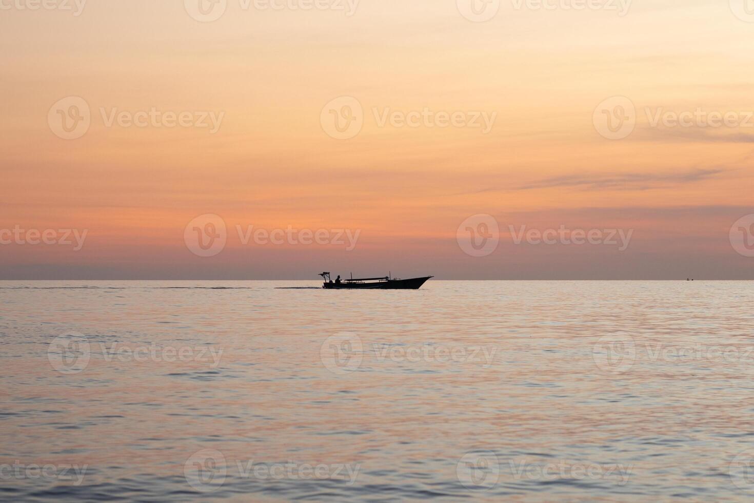 Silhouette of a fishing boat in the sea at sunset photo