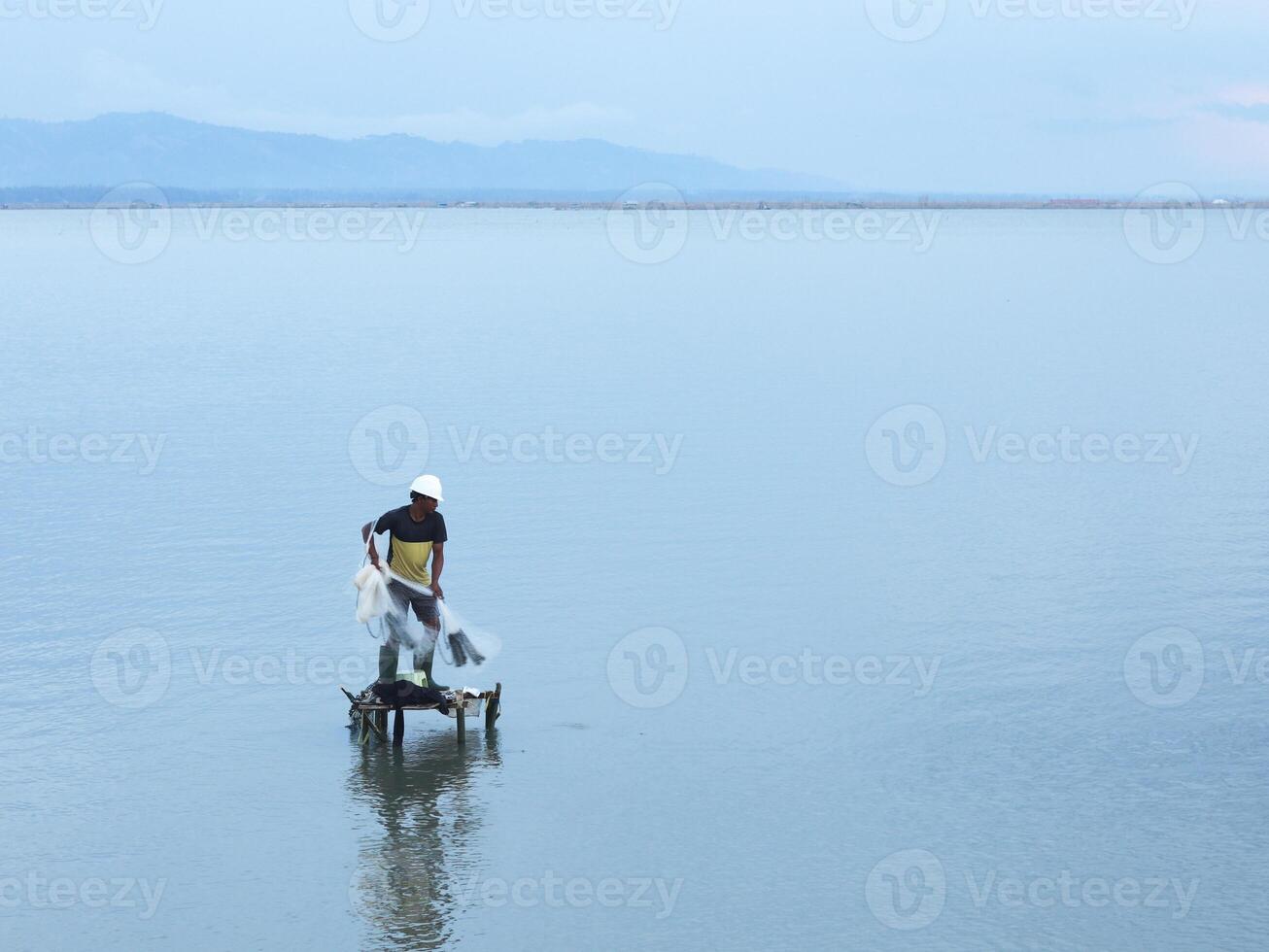 Fisherman catching fish with net on the lake in the morning, Gorontalo, Indonesia photo