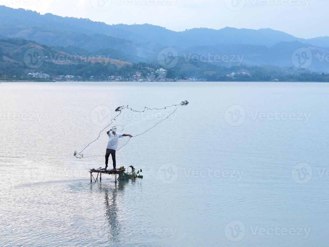 Fisherman catching fish with net on the lake in the morning, Gorontalo, Indonesia photo