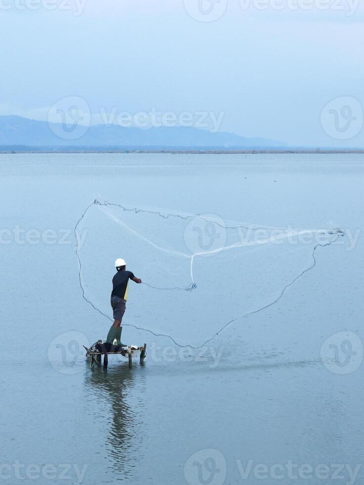 Fisherman catching fish with net on the lake in the morning, Gorontalo, Indonesia photo