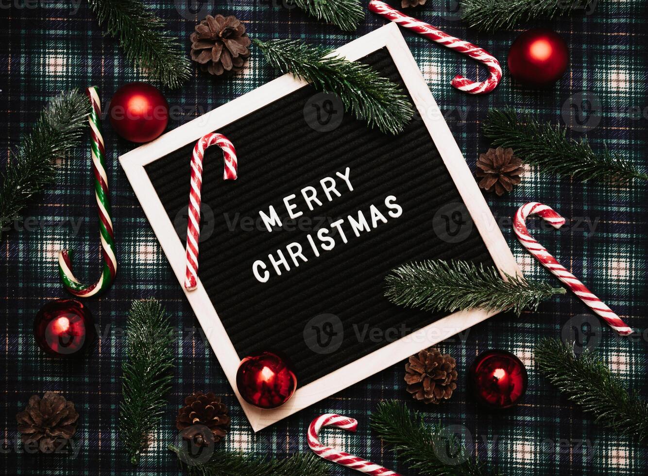 Merry Christmas lettering in plastic letters on an old vintage letter board. On the background there are caramel canes, balls, cones and fir branches. Top view. Flatley. Christmas greeting card. photo
