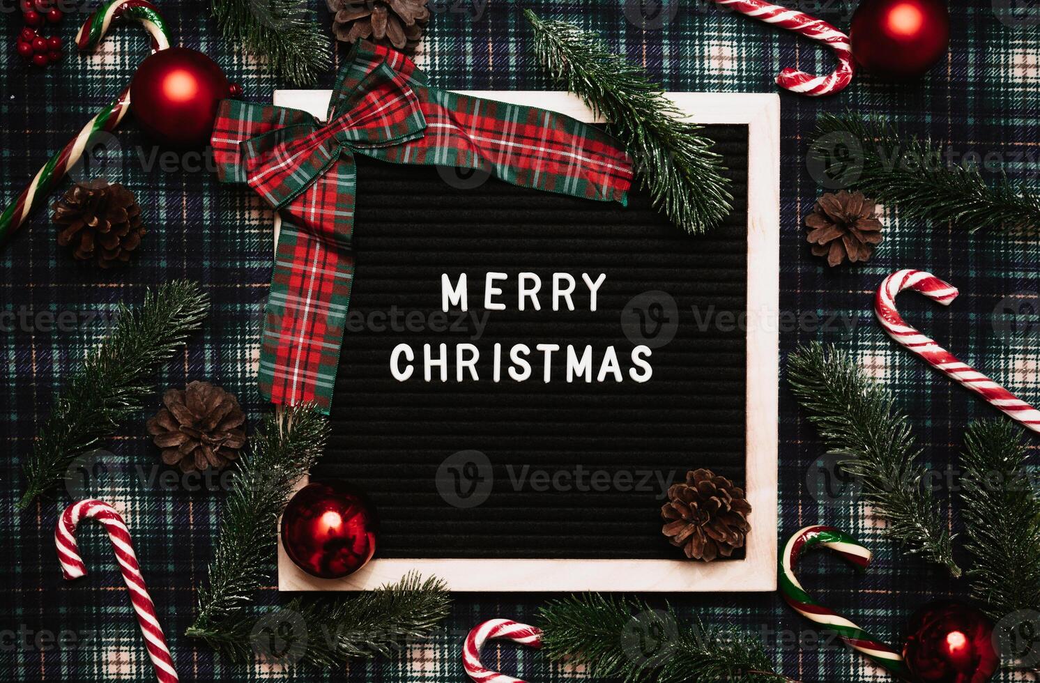 Merry Christmas lettering in plastic letters on an old vintage letter board. On the background there are caramel canes, balls, cones and fir branches. Top view. Flatley. Christmas greeting card. photo