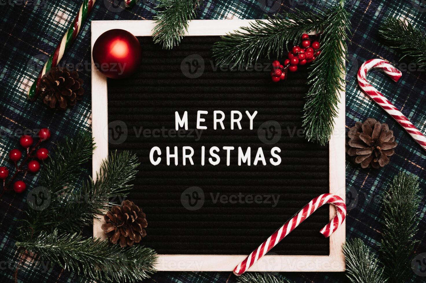 Merry Christmas lettering in plastic letters on an old vintage letter board. On the background there are caramel canes, balls, cones and fir branches. Top view. Flatley. Christmas greeting card. photo