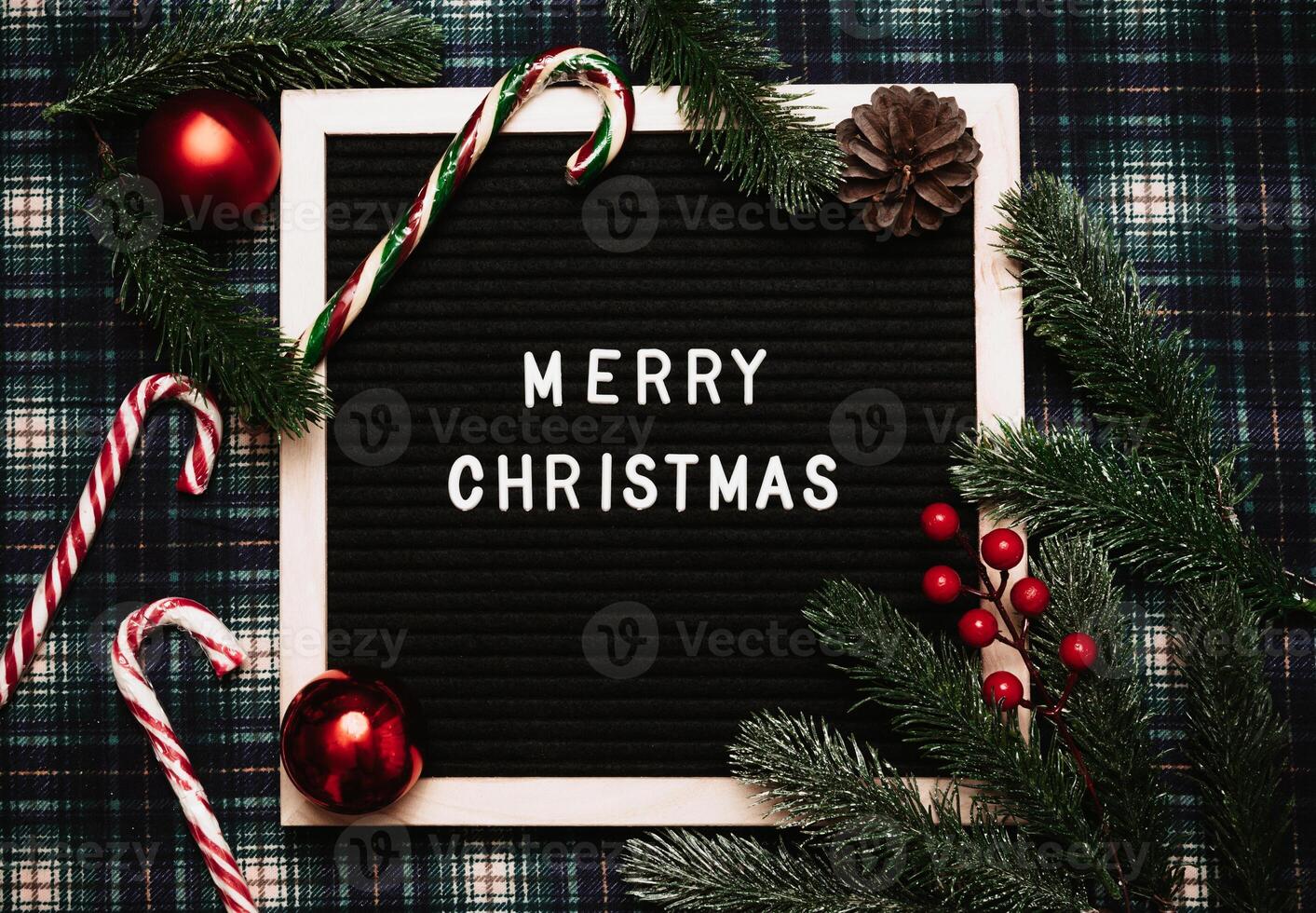 Merry Christmas lettering in plastic letters on an old vintage letter board. There are caramel canes, balls, cones and fir branches all around. Top view. Flatley. Ready-made Christmas greeting card. photo