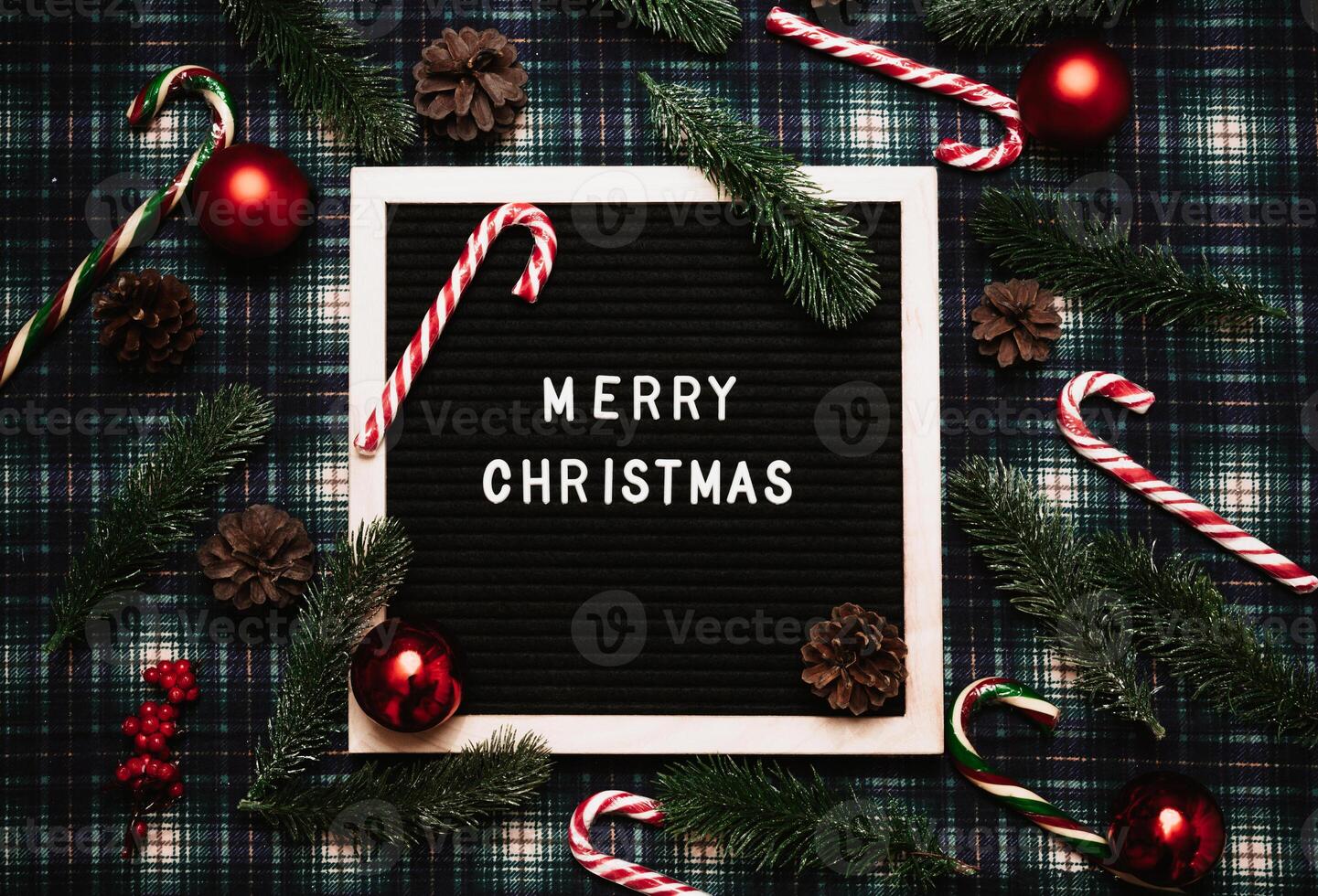 Merry Christmas lettering in plastic letters on an old vintage letter board. There are caramel canes, balls, cones and fir branches all around. Top view. Flatley. Ready-made Christmas greeting card. photo