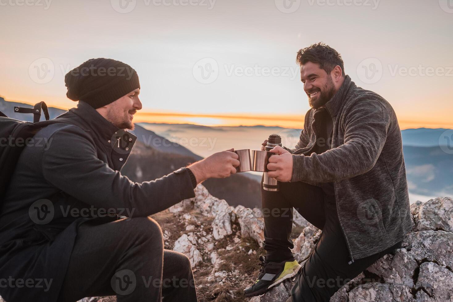 Two friends tourists are relaxing while drinking a cup of coffee or tea during the hike on the mountain active healthy lifestyle adventure travel. photo