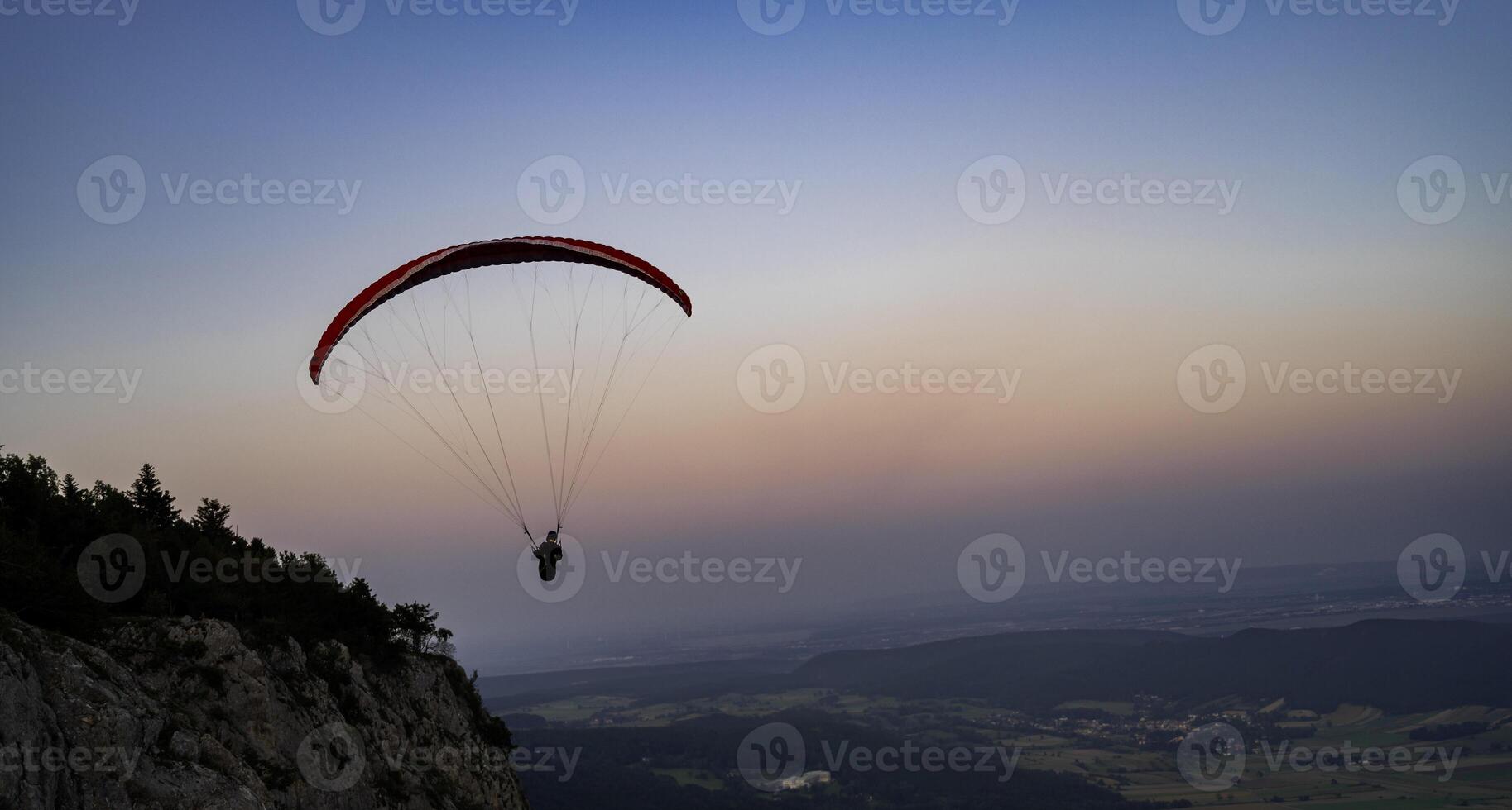 Paragliding concept, a paraglider pilot fly in the sky at sunset on the nature mountain landscape background. photo
