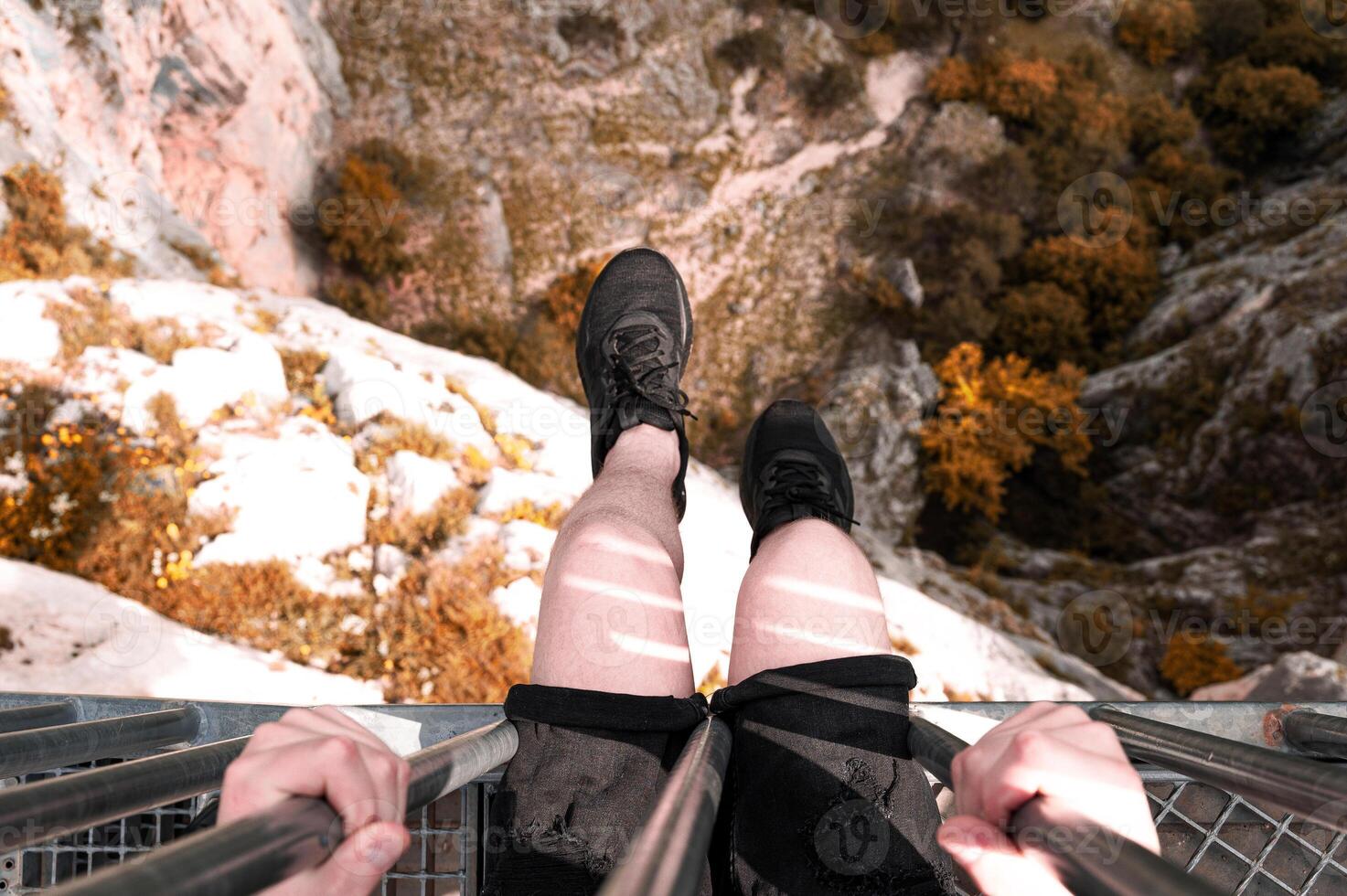 A man traveler sitting on cliff bridge edge with forest mountain aerial view adventure travel. photo