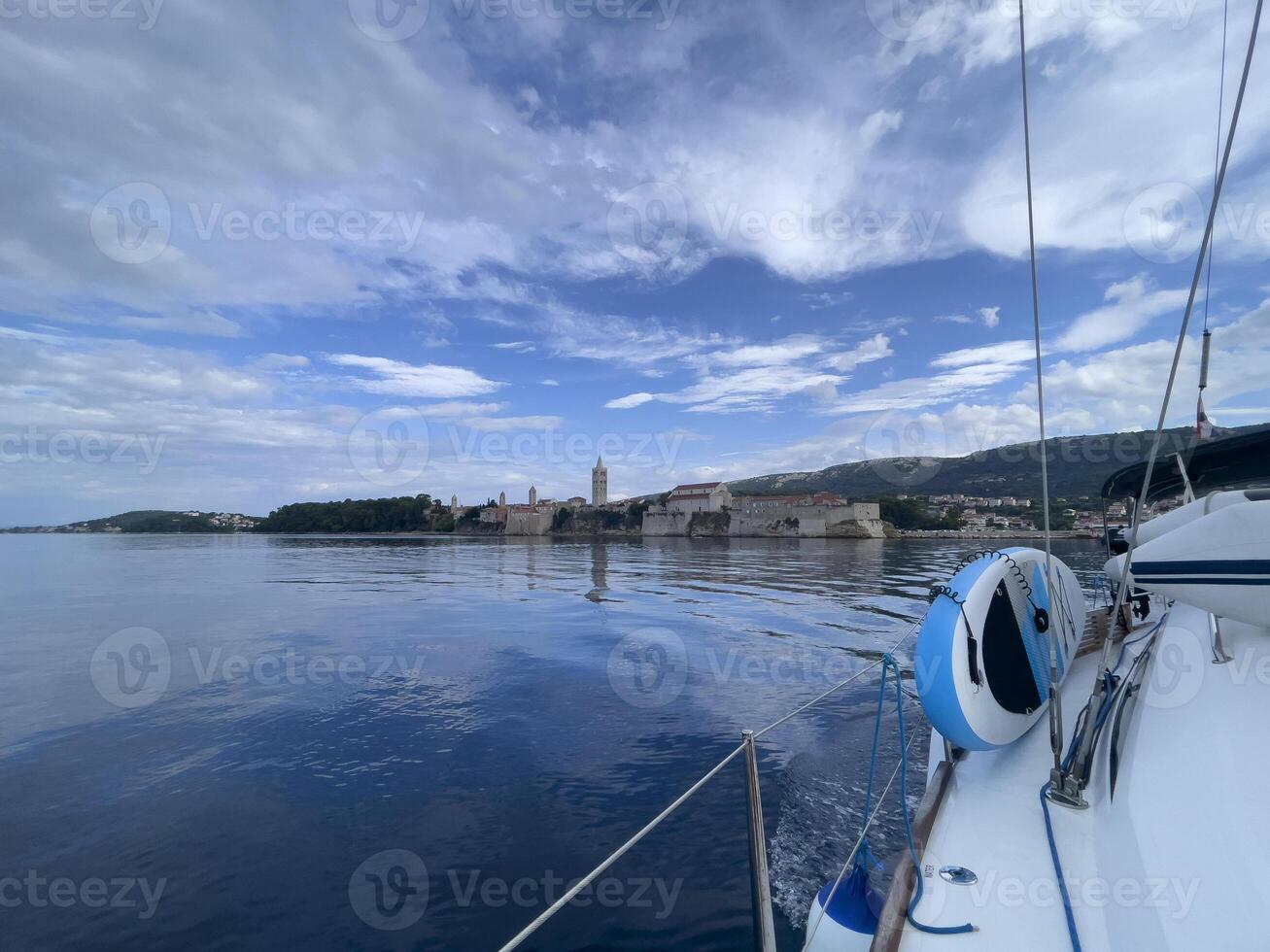 a sailboat in the water with a town in the background photo