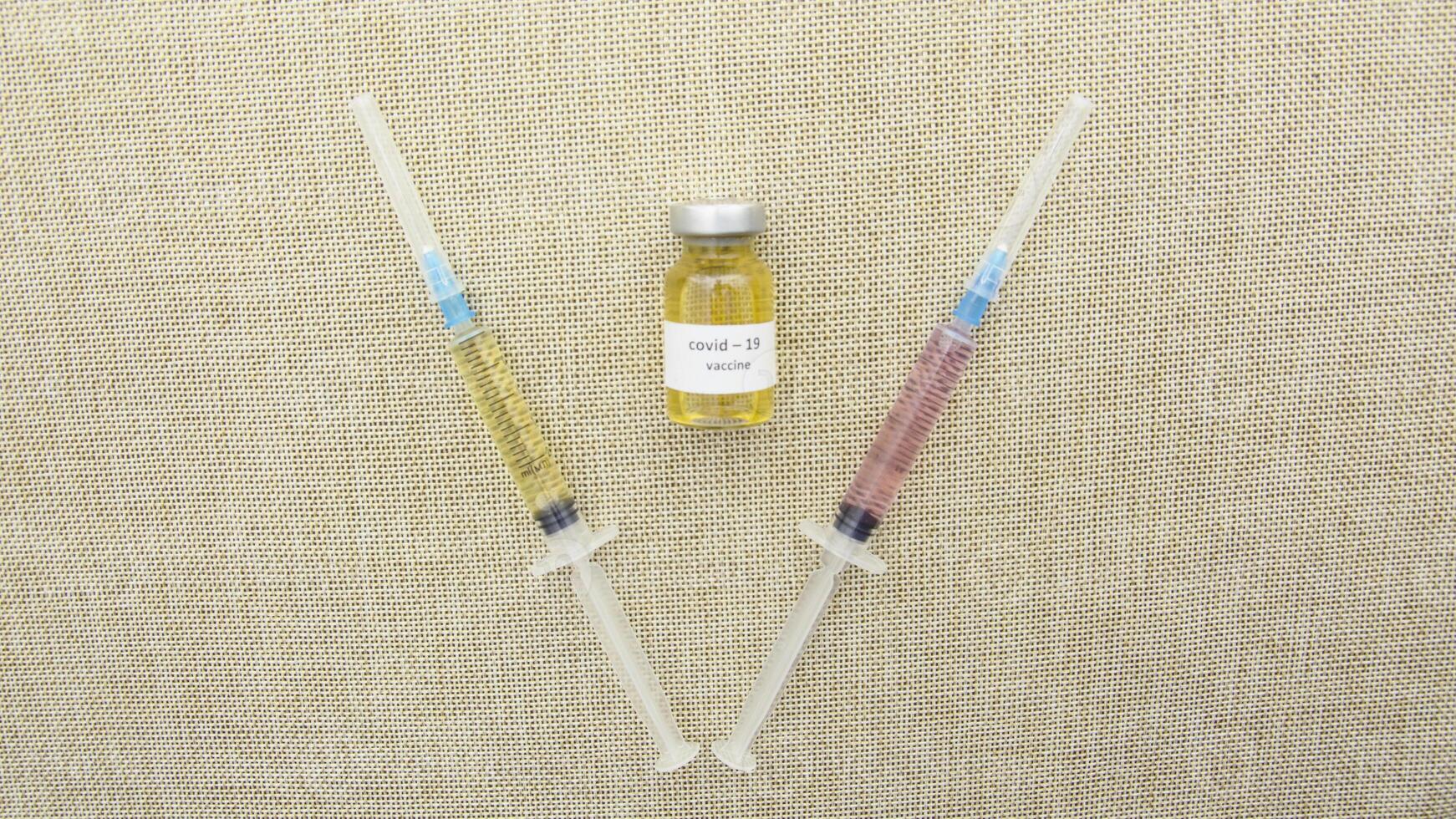 A syringe and a bottle of liquid next to each other photo
