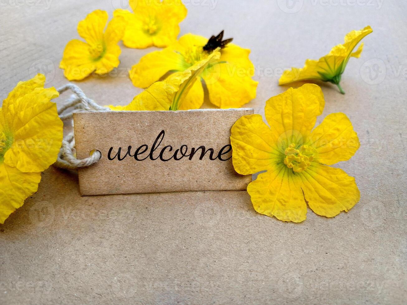 written welcome on a cardboard tag with yellow flowers, welcome sign background photo
