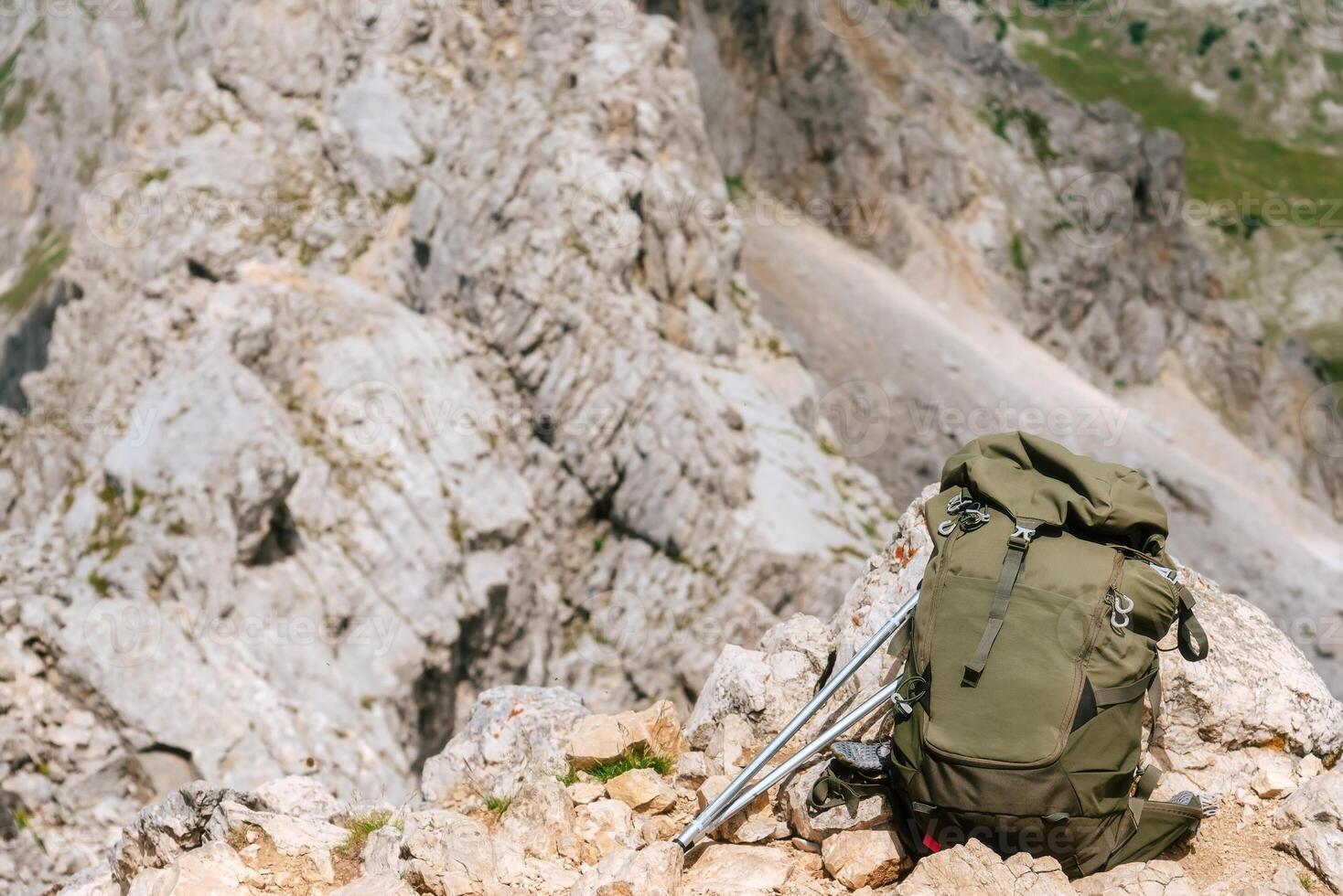Hiking Backpack and Trekking Poles on Rock in Mountains photo