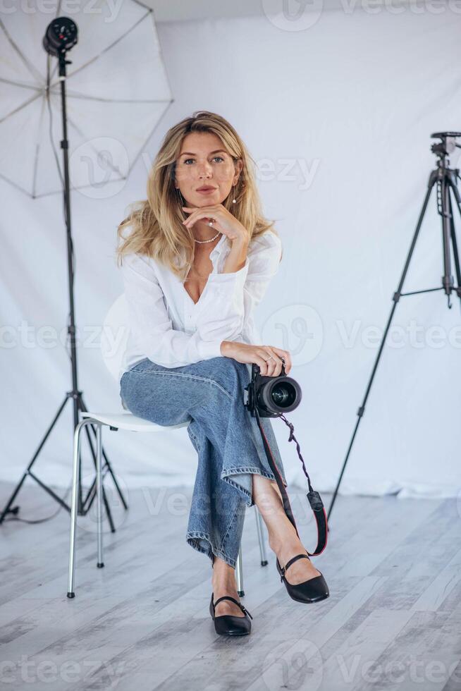 A young female photographer holding a camera in a well-lit studio, capturing the perfect shot with a focused expression photo