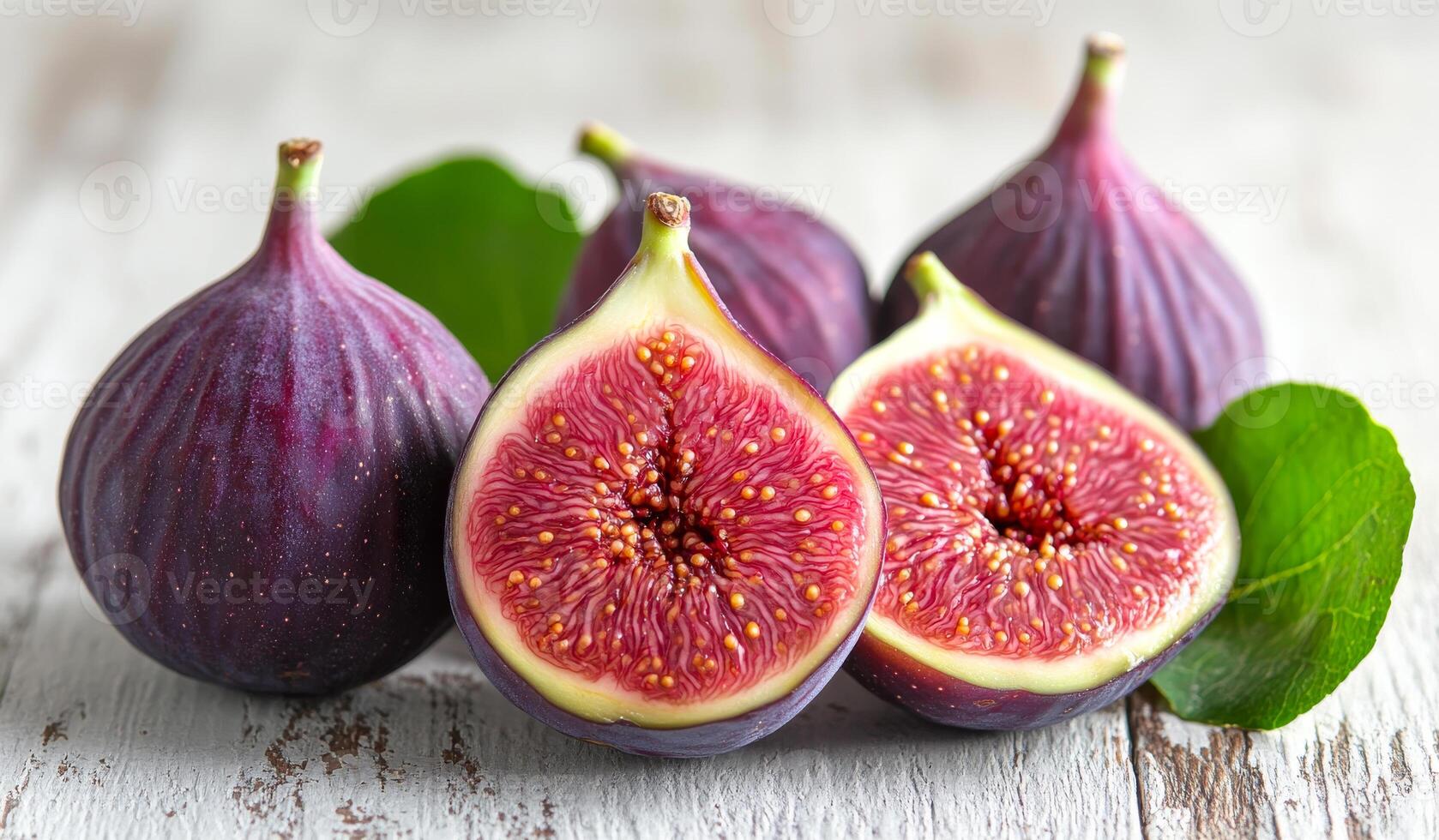 A bunch of purple figs with one cut open. The figs are ripe and ready to eat photo